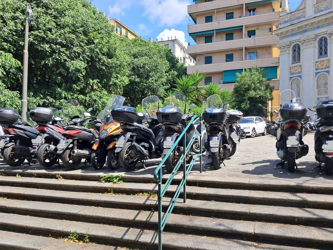 Marassi, piazzale della chiesa invaso dagli scooter, saranno stati multati? marassi sosta selvaggia scooter partita